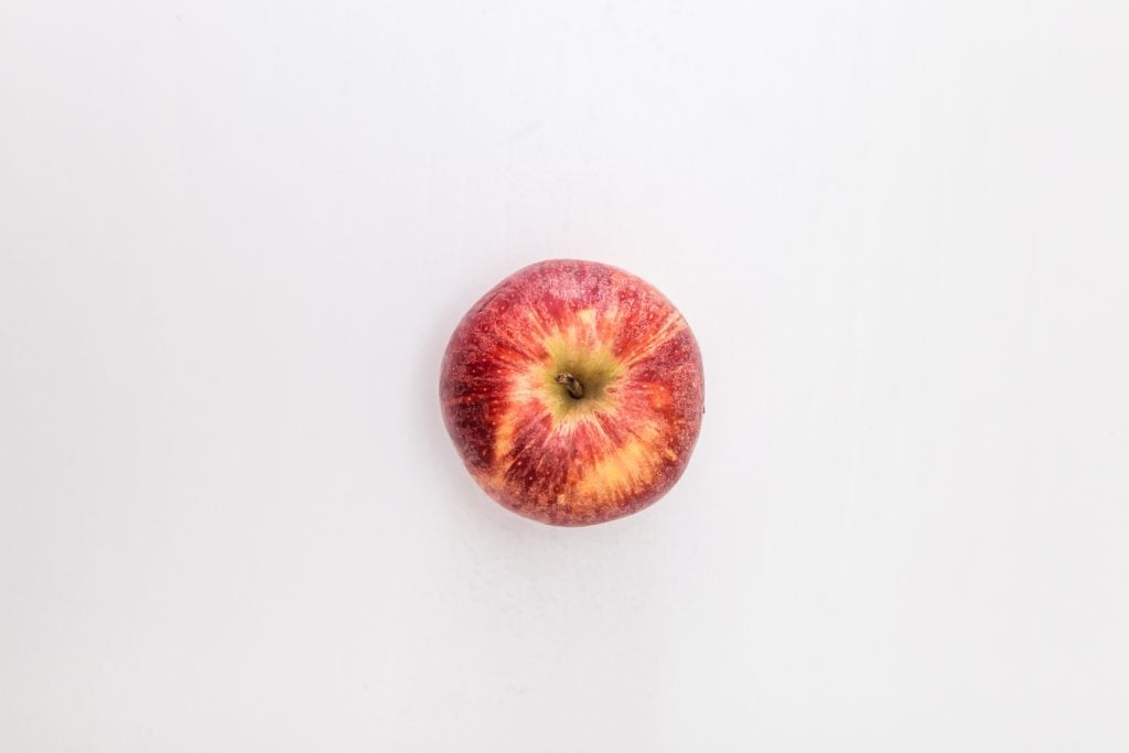 red apple fruit on white table